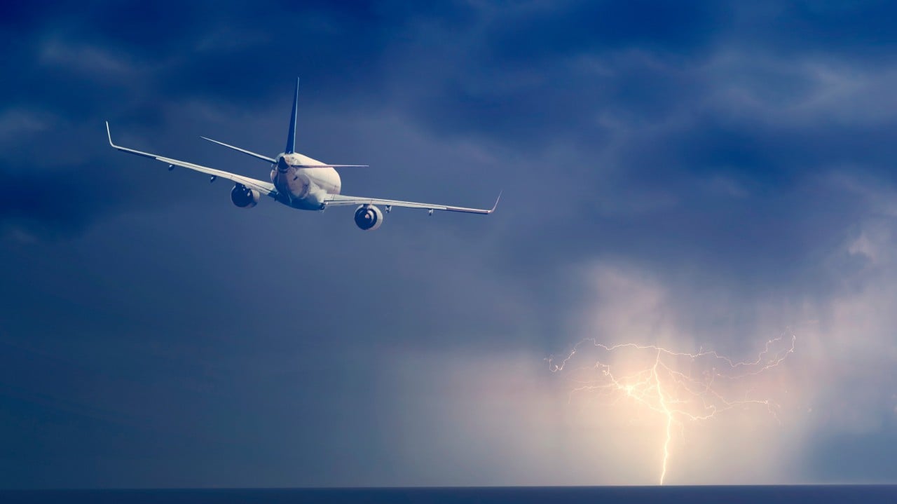 Passenger airplane flying above sea on stormy sky with dark clouds and lightnings. By R [Adobe Stock Photos]
