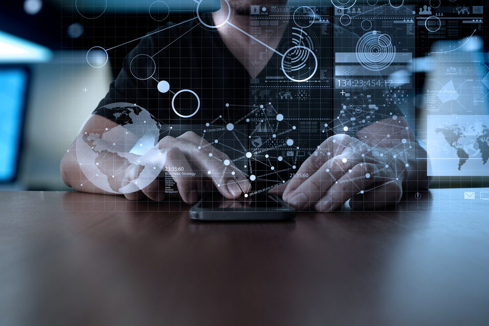 person using a small tablet with an illustration of technology floating around him