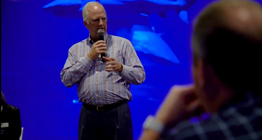 tony holding a microphone in front of a blue background