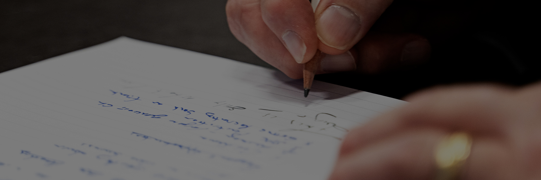 close up of a hand writing a note on a sheet of paper