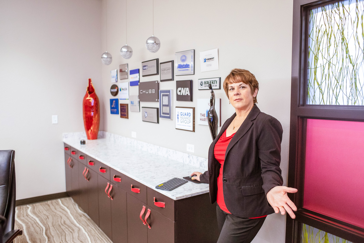 woman presenting a wall of certificates