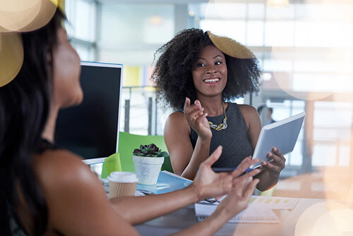 2 women speaking at a desk